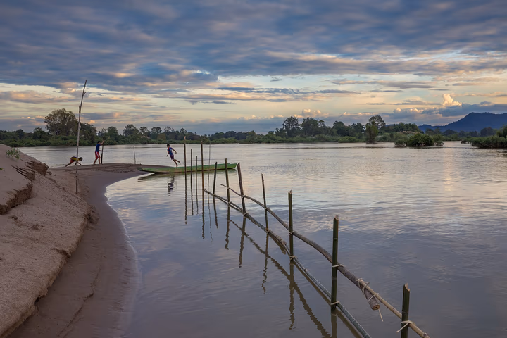 Children playing at sunset on a riverbank