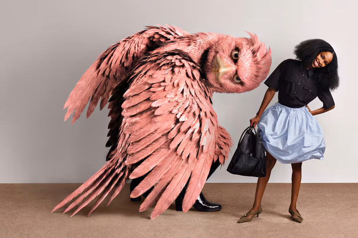 A large, pink bird-like creature and a model wearing Prada both lean to the side in similar poses.